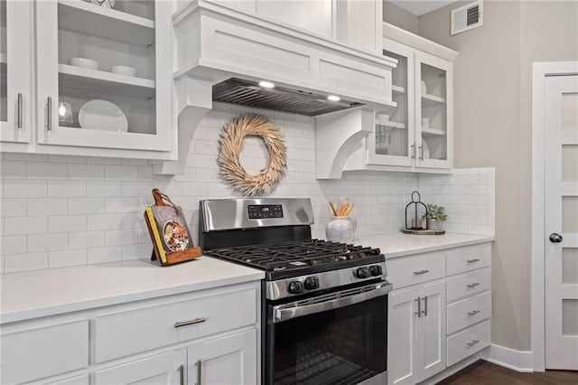 kitchen with gas stove, dark hardwood / wood-style floors, decorative backsplash, white cabinets, and custom exhaust hood