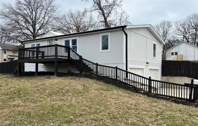 rear view of house featuring a garage, a yard, and a deck