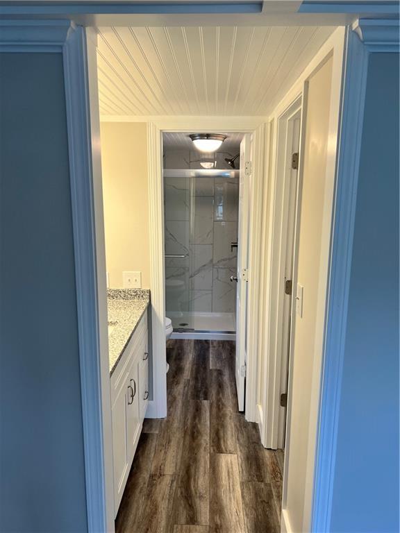 bathroom with vanity, wood-type flooring, a shower with shower door, and toilet