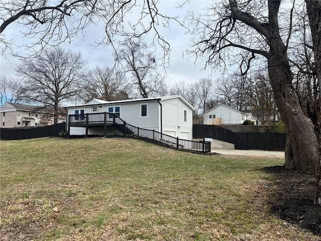 rear view of property with a garage, a deck, and a lawn