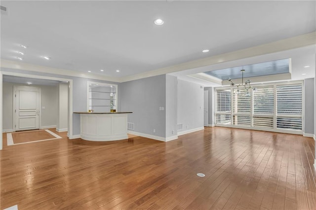 433 Ward Pkwy Unit 3S, Kansas City, MO 64112 - unfurnished living room featuring a chandelier, wood-type flooring, ornamental molding, a tray ceiling, and recessed lighting