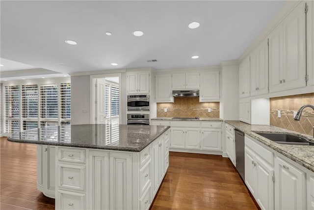 433 Ward Pkwy Unit 3S, Kansas City, MO 64112 - kitchen featuring under cabinet range hood, dark wood-style floors, appliances with stainless steel finishes, a kitchen island, and recessed lighting
