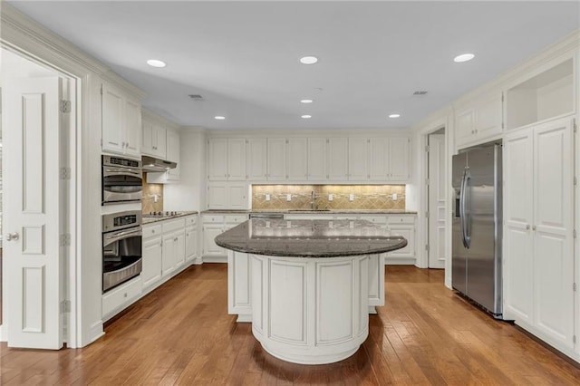 433 Ward Pkwy Unit 3S, Kansas City, MO 64112 - kitchen featuring appliances with stainless steel finishes, dark stone counters, hardwood / wood-style flooring, a kitchen island, and recessed lighting