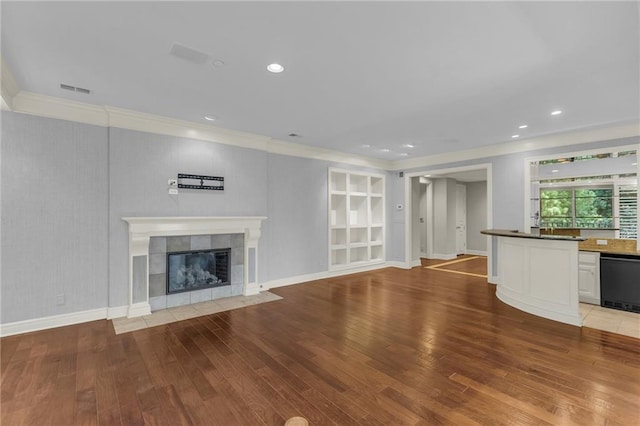 433 Ward Pkwy Unit 3S, Kansas City, MO 64112 - unfurnished living room featuring crown molding, wood finished floors, a tile fireplace, and recessed lighting
