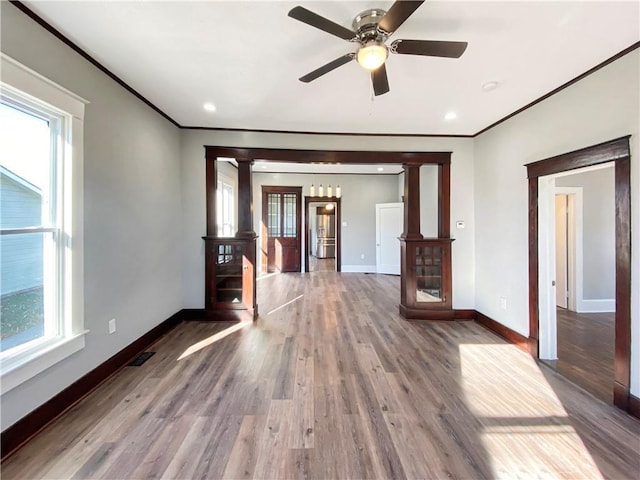 unfurnished living room with hardwood / wood-style flooring, plenty of natural light, and decorative columns