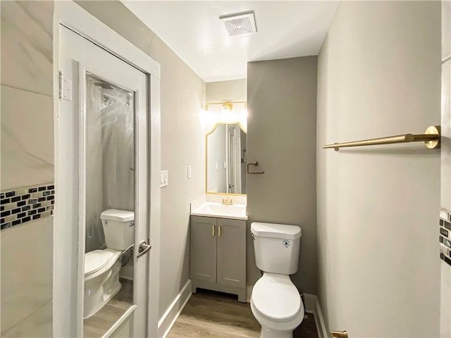 bathroom with vanity, hardwood / wood-style flooring, toilet, and tasteful backsplash