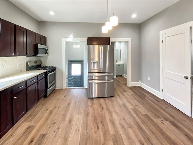 kitchen featuring light hardwood / wood-style floors, hanging light fixtures, and appliances with stainless steel finishes