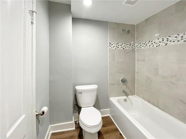 bathroom with toilet, wood-type flooring, and tiled shower / bath