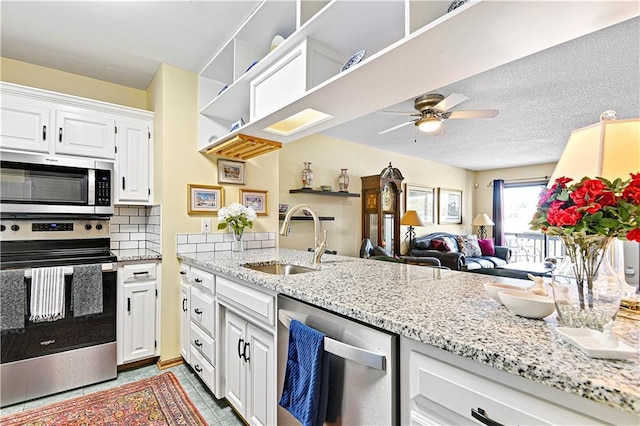 kitchen featuring appliances with stainless steel finishes, backsplash, ceiling fan, sink, and white cabinetry