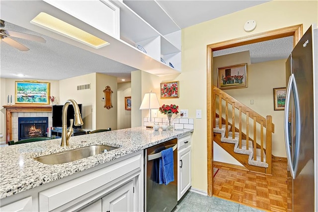 kitchen featuring sink, stainless steel appliances, light stone counters, a textured ceiling, and white cabinets