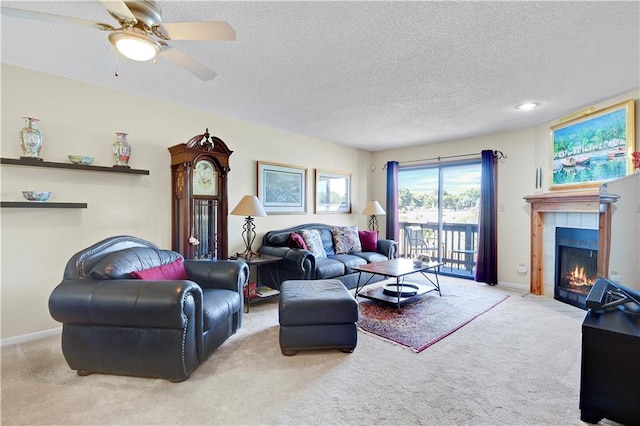 living room with a tiled fireplace, light carpet, ceiling fan, and a textured ceiling