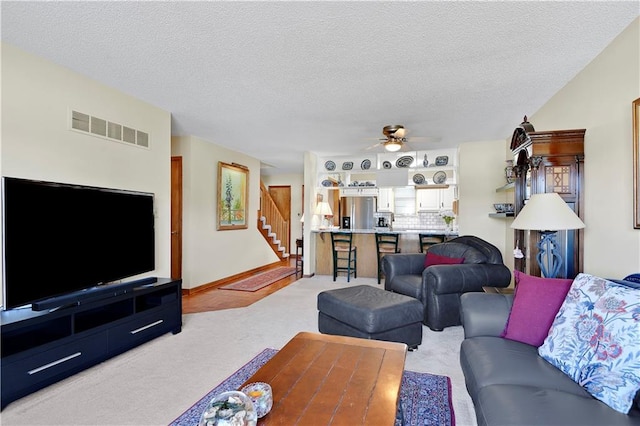 living room featuring a textured ceiling, light colored carpet, and ceiling fan