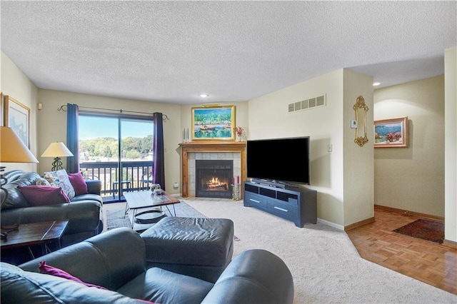 living room with a tile fireplace, a textured ceiling, and parquet flooring