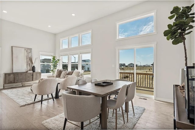 dining area with a high ceiling and light hardwood / wood-style flooring