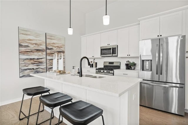 kitchen featuring white cabinetry, a center island with sink, stainless steel appliances, and decorative light fixtures