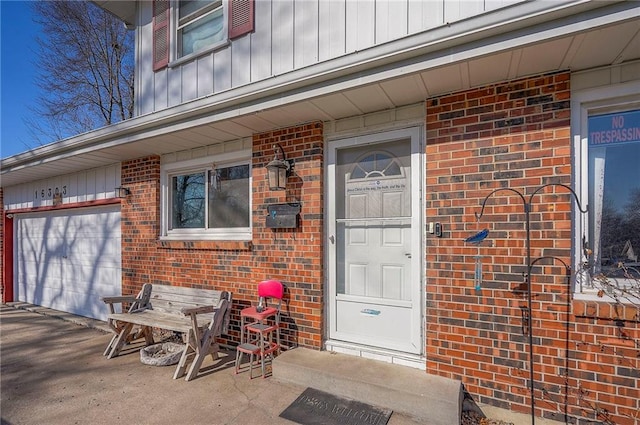 property entrance featuring brick siding, board and batten siding, and an attached garage