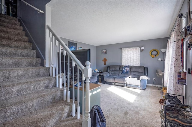 carpeted living area with stairway, baseboards, and a textured ceiling