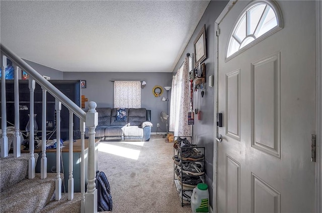 carpeted entryway with stairway, baseboards, and a textured ceiling