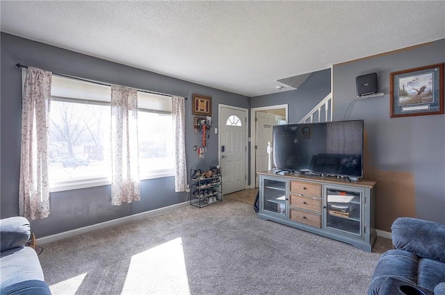 carpeted living area with a textured ceiling and baseboards