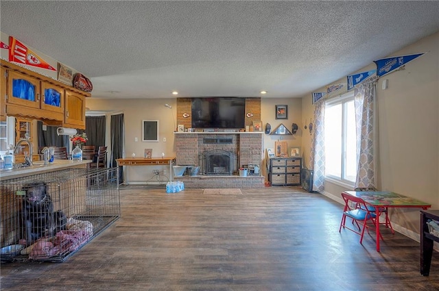 living area featuring a textured ceiling, wood finished floors, recessed lighting, a fireplace, and baseboards