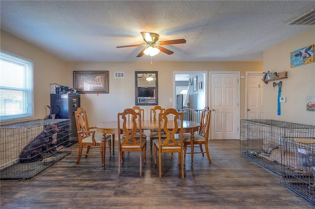 dining room with visible vents, a textured ceiling, wood finished floors, and a ceiling fan