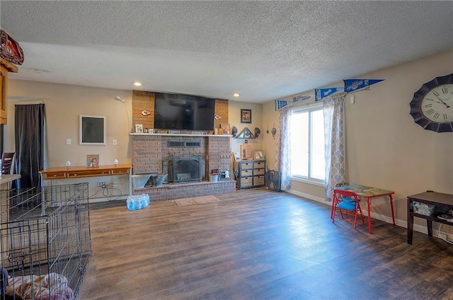 living area with wood finished floors, baseboards, a fireplace, recessed lighting, and a textured ceiling