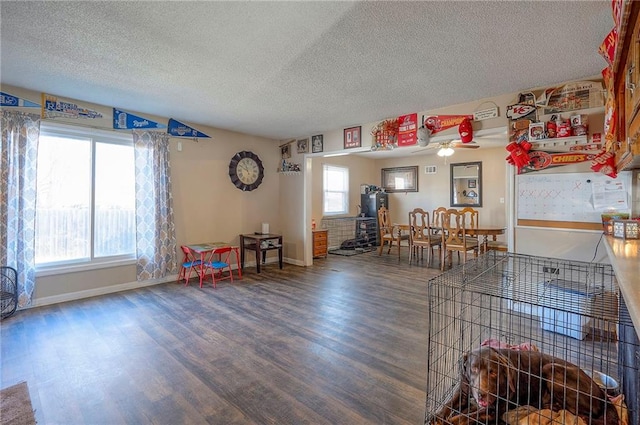 recreation room featuring ceiling fan, baseboards, a textured ceiling, and wood finished floors