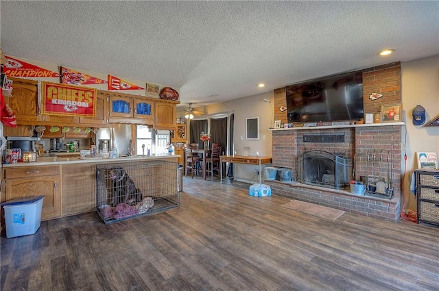 kitchen with brown cabinets, a fireplace, a peninsula, dark wood-style floors, and a ceiling fan