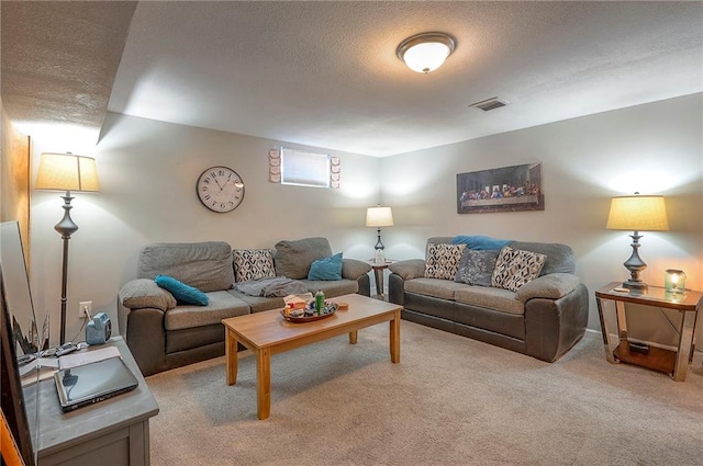 living room featuring visible vents, light colored carpet, and a textured ceiling