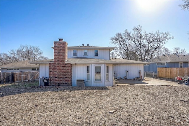 back of property with central AC unit, fence private yard, and a chimney