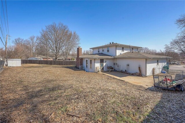 back of house with a lawn, a chimney, and fence