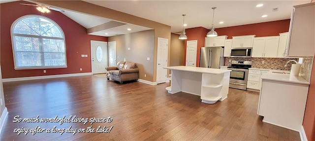 kitchen featuring pendant lighting, a center island, lofted ceiling, dark wood-type flooring, and appliances with stainless steel finishes