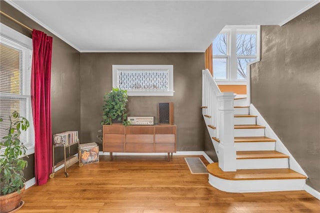 stairs featuring hardwood / wood-style floors and crown molding