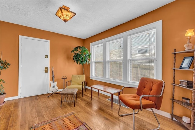 living area with a textured ceiling and light wood-type flooring