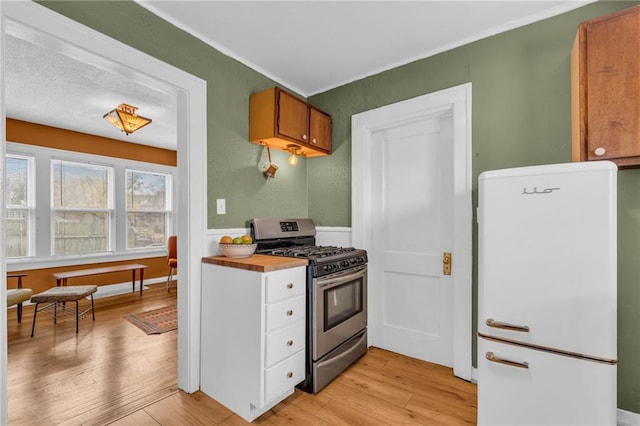 kitchen with gas stove, wooden counters, white refrigerator, and light hardwood / wood-style flooring