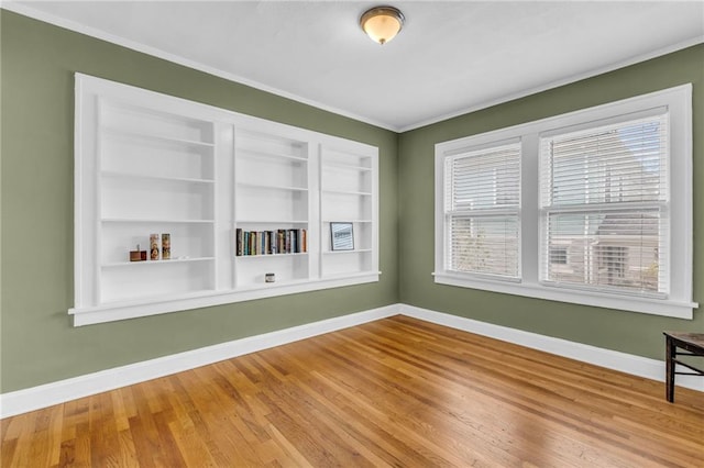 spare room with crown molding, hardwood / wood-style floors, and built in features