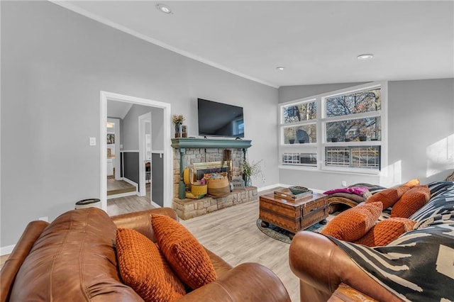 living room with a stone fireplace, light hardwood / wood-style floors, and lofted ceiling