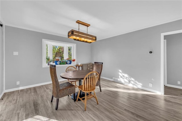 dining area with wood-type flooring and crown molding