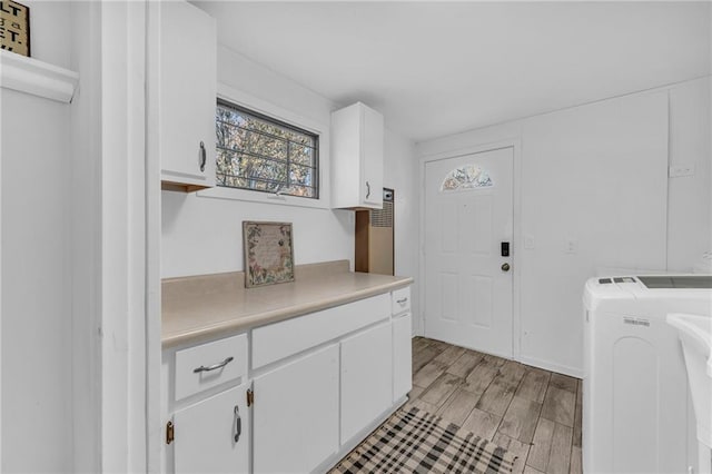 washroom with washer and dryer, cabinets, and light wood-type flooring