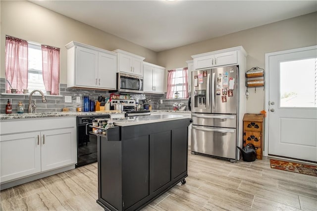 kitchen with light stone countertops, white cabinets, appliances with stainless steel finishes, sink, and backsplash