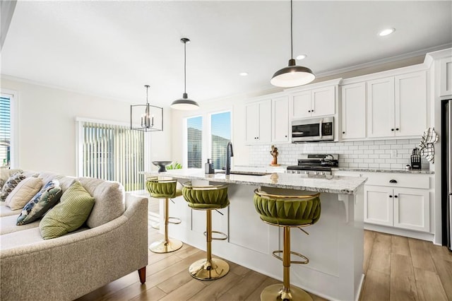 kitchen featuring white cabinetry, a kitchen island with sink, pendant lighting, and stainless steel appliances