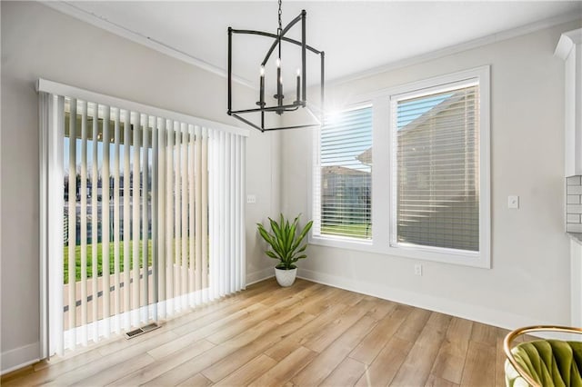 dining area with a chandelier, a wealth of natural light, crown molding, and light hardwood / wood-style floors