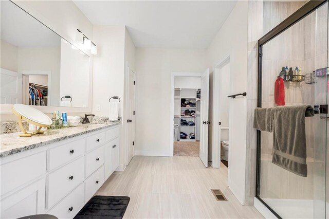 20915 W 190th Ter, Spring Hill, KS 66083 - bathroom with a walk in closet, double vanity, a shower stall, toilet, and baseboards