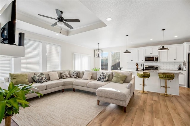 living room with light hardwood / wood-style flooring, ceiling fan, and ornamental molding