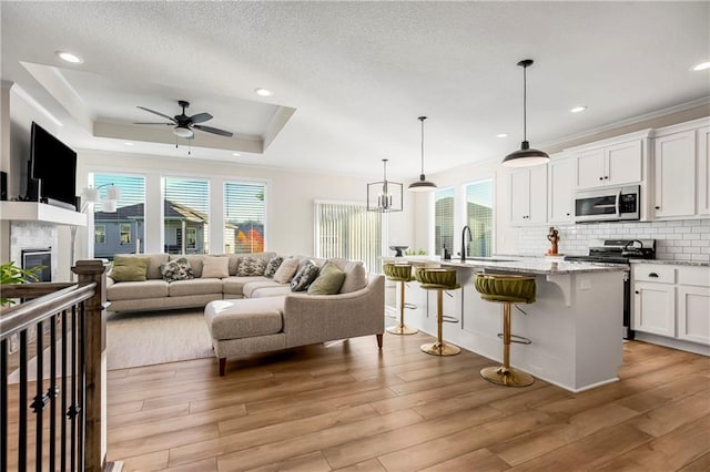 kitchen with appliances with stainless steel finishes, a center island with sink, white cabinets, light hardwood / wood-style floors, and a breakfast bar area