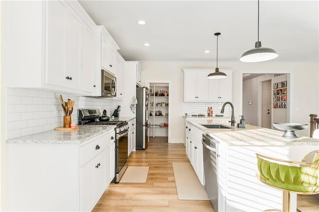 kitchen with white cabinetry, pendant lighting, stainless steel appliances, and light wood-type flooring