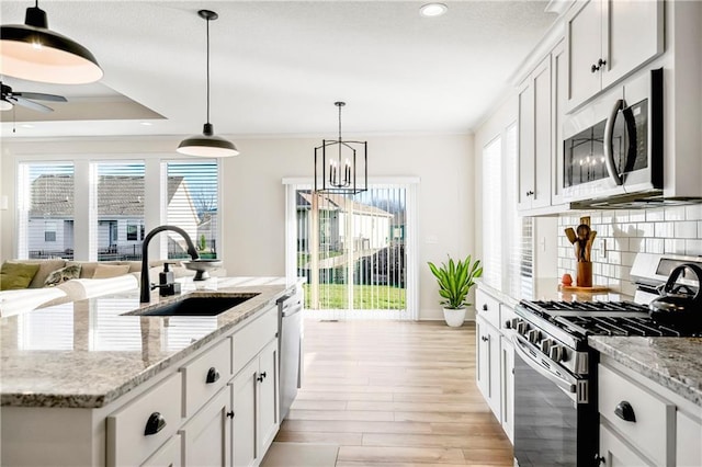 kitchen with decorative backsplash, appliances with stainless steel finishes, light stone counters, sink, and white cabinetry