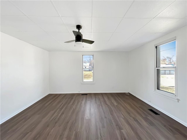 empty room featuring a healthy amount of sunlight, ceiling fan, and dark wood-type flooring