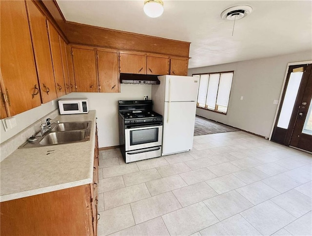 kitchen with light tile patterned floors, white appliances, and sink