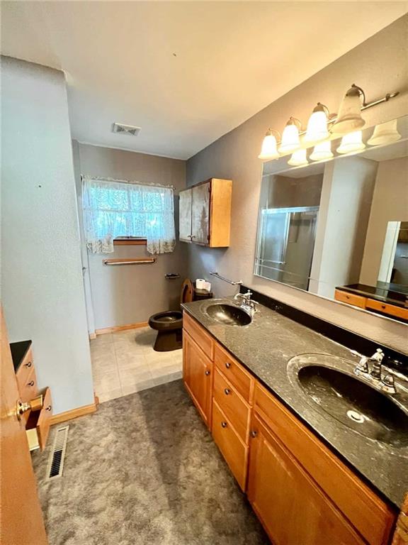 bathroom with tile patterned floors, vanity, an enclosed shower, and toilet